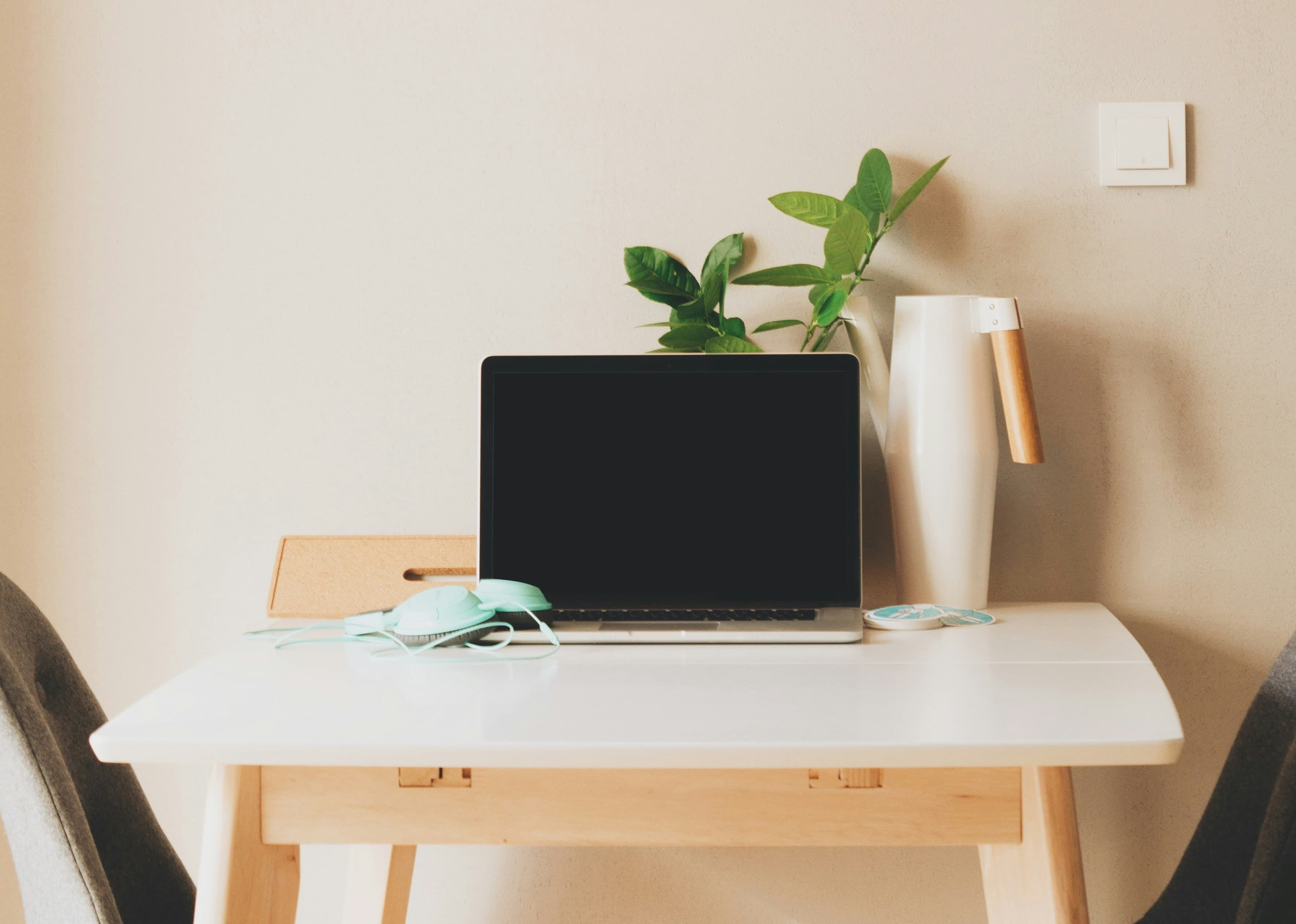 Een bureau met een laptop, notitieboek en een kop koffie